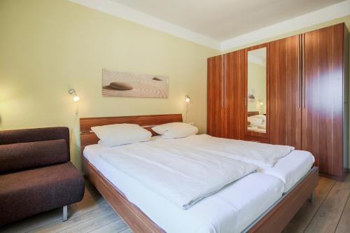 a bedroom with a large white bed and a chair at Ferienhof Büdlfarm - Treckerschuppen in Sahrensdorf