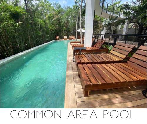 a swimming pool with wooden benches in the water at Casa Xaman in Tulum - TH 5 in Tulum