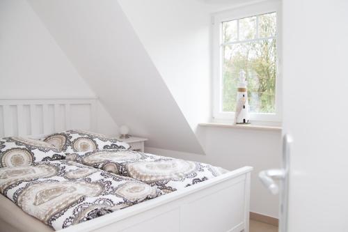 a white bedroom with a bed and a window at Carpe Diem Dahme in Dahme