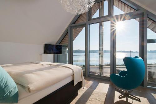 ハイリゲンハーフェンにあるOstsee - Reetdachhaus Nr 3 "Südstrand Lodge Marina-Bay" im Strand Resortのベッドルーム1室(ベッド1台、青い椅子付)