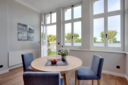 a dining room with a table and chairs and windows at Villa Seeblick "Wolgastsee" in Ahlbeck