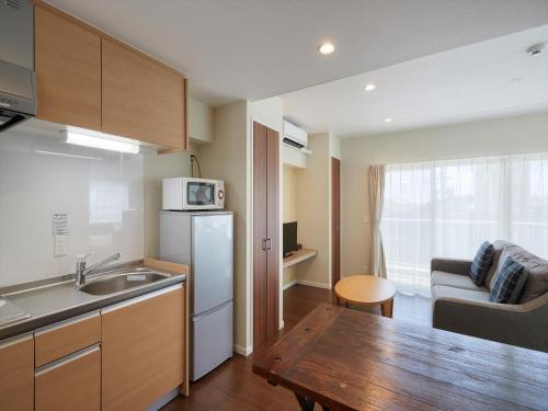 a kitchen and living room with a table and a refrigerator at Seaside Condominium Rana Chatan in Chatan