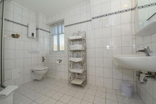 ヴィーク・アウフ・フェールにあるHaus Amselnest Whg 03の白いタイル張りのバスルーム(トイレ、シンク付)