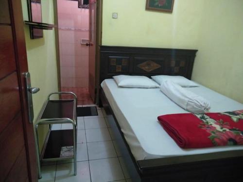 um pequeno quarto com uma cama e uma cabina de duche ao nível do chão em Villa Trijaya em Batu