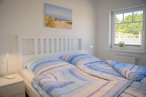 ein Schlafzimmer mit einem Bett mit gestreifter Bettwäsche und einem Fenster in der Unterkunft Scheune 9 in Gollendorf