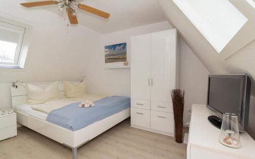 ein weißes Schlafzimmer mit einem Bett und einem TV in der Unterkunft Dorfoase - a56995 in Sankt Peter-Ording