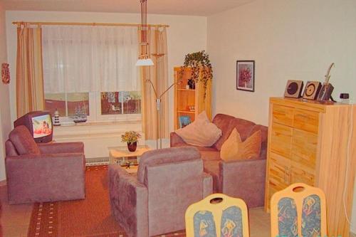 uma sala de estar com um sofá e duas cadeiras em Am Deich 33 em Zingst