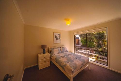 een slaapkamer met een bed en een groot raam bij Orana ~ 2 blocks to Beach ~ FREE Wifi in Apollo Bay