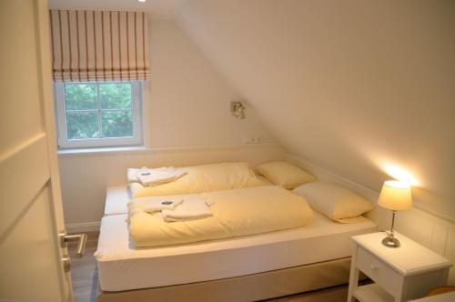 ein Schlafzimmer mit einem Bett mit gelber Bettwäsche und einem Fenster in der Unterkunft Am Maisfeld Ferienhaus in Wyk auf Föhr