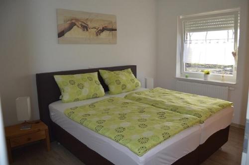 ein Schlafzimmer mit einem Bett mit einer gelben Decke und einem Fenster in der Unterkunft Haus Storchennest in Wiefelstede