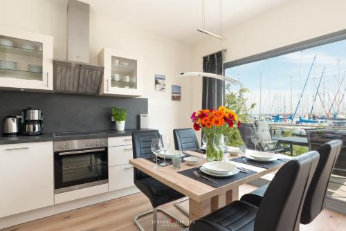 eine Küche und ein Esszimmer mit einem Tisch mit Blumen darauf in der Unterkunft Ostsee - Maisonette - Appartement Nr 48 "Hafenblick" im Strand Resort in Heiligenhafen