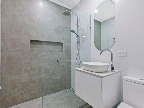 a bathroom with a shower and a sink and a mirror at Blue Pacific Apartment 8 in The Entrance
