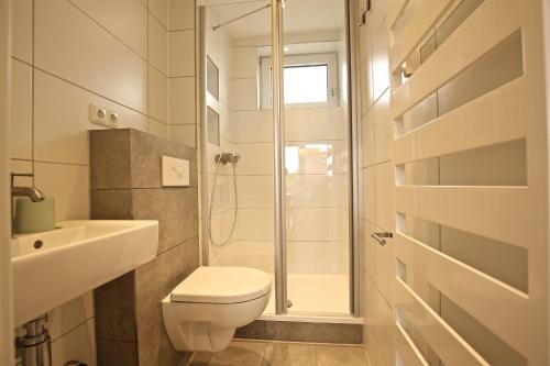 biała łazienka z toaletą i prysznicem w obiekcie Ferienwohnung Leuchtturmblick w mieście Wangerooge