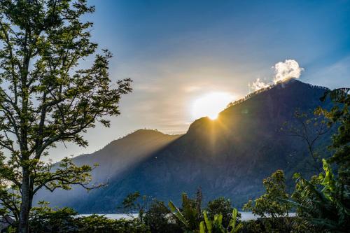 a view of a mountain with the sun shining on it at Pondok Manoka in Kintamani