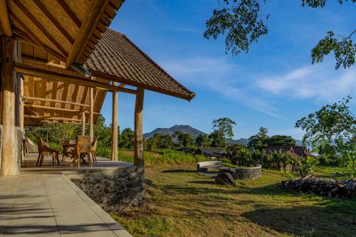 a porch of a house with tables and chairs at Pondok Manoka in Kintamani