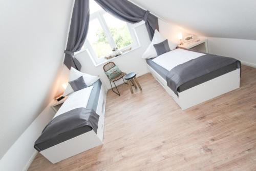 ein kleines Schlafzimmer im Dachgeschoss mit 2 Betten und einem Fenster in der Unterkunft Adams Kajüte in Krummhörn