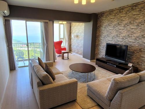 a living room with two couches and a flat screen tv at Hotel Village Izukogen in Ito