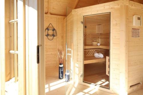 a wooden sauna with a glass door in a room at FEWO Kornblume in Hohen Wieschendorf