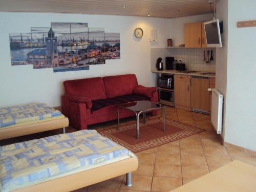 een woonkamer met een rode bank en een keuken bij Appartement Altes Land Jork bei HH in Jork