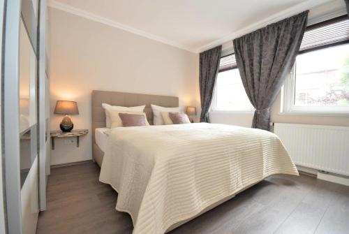 a white bedroom with a large bed and two windows at Business Apartments Bremen Typ 3 in Bremen
