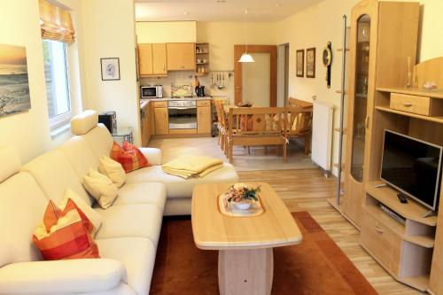 ein Wohnzimmer mit einem weißen Sofa und einem Tisch in der Unterkunft Haus am Grömitzer Deich - Whg 4 in Grömitz