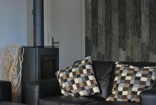 a black couch with checkered pillows in a living room at Fehmarn-OstseeferienStrandresidenz VogelflugApp 10 in Fehmarnsund