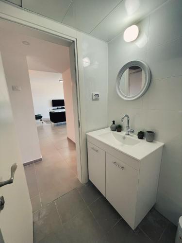 a white bathroom with a sink and a mirror at דירת נופש ׳חושן׳ in Eilat