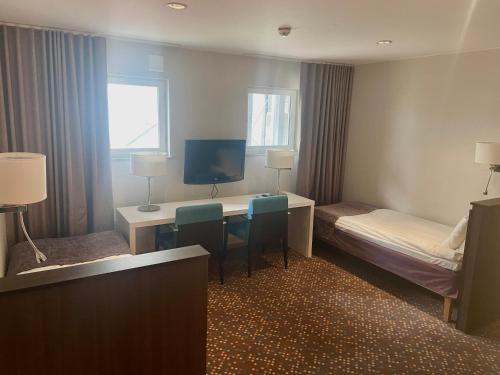 a hotel room with a desk and a bed and a tv at Hotel Finn in Lund