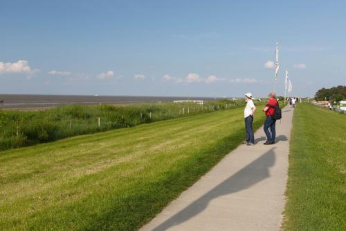 two people walking on a path next to a field at Hotel Seeschwalbe in Cuxhaven