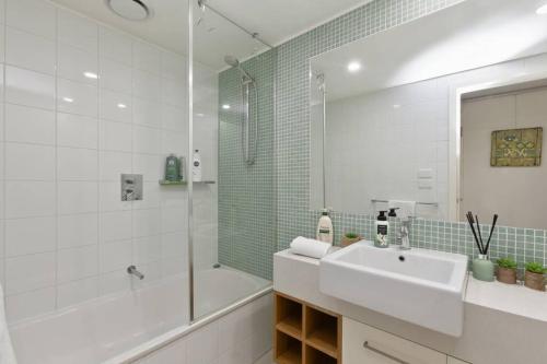 a white bathroom with a sink and a shower at Apollo Blue Pearl ~ Oceanfront ~ Free Wifi in Apollo Bay