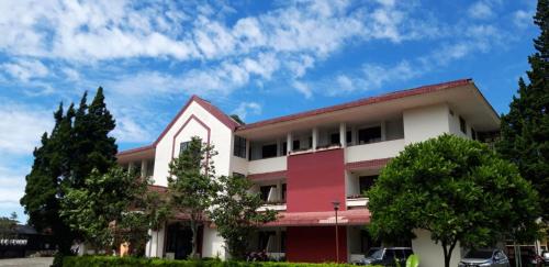 a red and white building with trees in front of it at Dieng Kledung Pass Hotel & Restaurant in Wonosobo