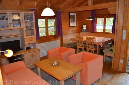 a living room with orange chairs and a dining room at Blockhaus Hedwig Haus 10 in Stamsried