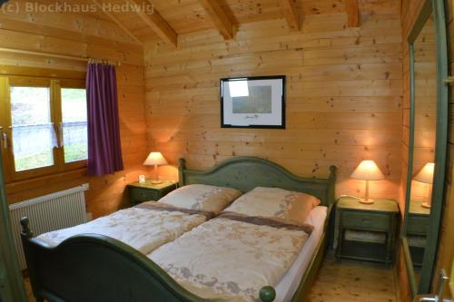 1 dormitorio con 1 cama en una pared de madera en Blockhaus Hedwig Haus 10, en Stamsried