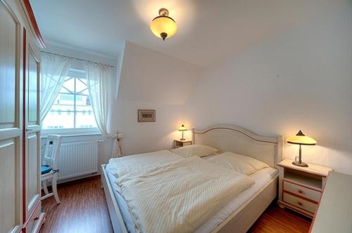 a bedroom with a large white bed with two lamps at Villa Carpe Diem, FW 8 in Zingst