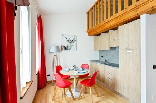 a small kitchen with a table and red chairs at Gressoney Saint-Jean apartments by Halldis in Gressoney-Saint-Jean