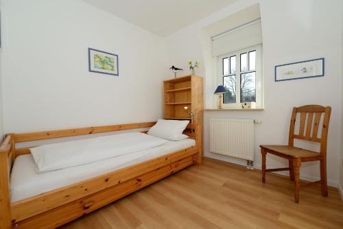 ein Schlafzimmer mit einem Holzbett und einem Stuhl in der Unterkunft Haus Amselnest Whg 04 in Wyk auf Föhr