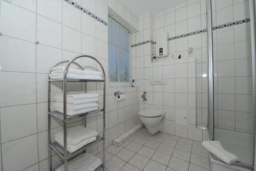 ein weiß gefliestes Bad mit einem WC und einer Dusche in der Unterkunft Haus Amselnest Whg 04 in Wyk auf Föhr