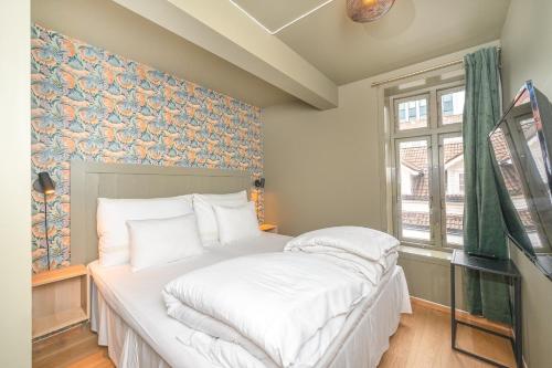 a bedroom with a bed with white sheets at GamlaVærket Gjæstgiveri og Tracteringssted in Sandnes