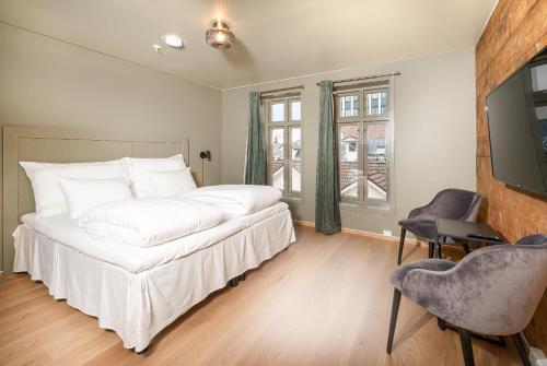 a bedroom with a white bed and a television at GamlaVærket Gjæstgiveri og Tracteringssted in Sandnes