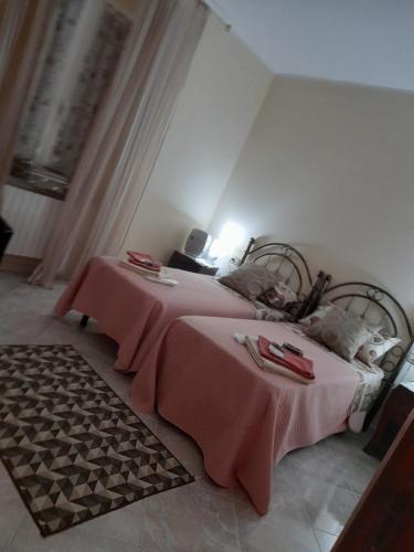 a bedroom with two beds with pink sheets and a rug at Locanda 130 in Fonni