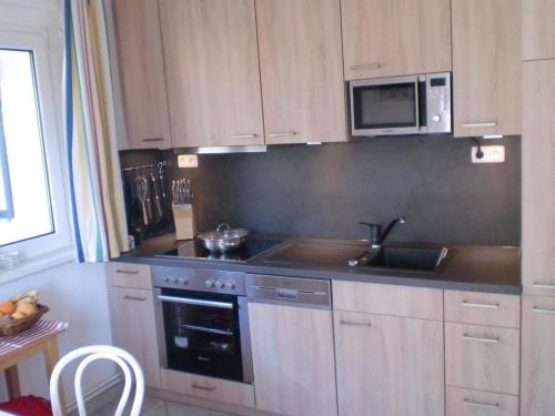 a kitchen with a stove and a sink and a microwave at Ostseebrise 1 in Zingst