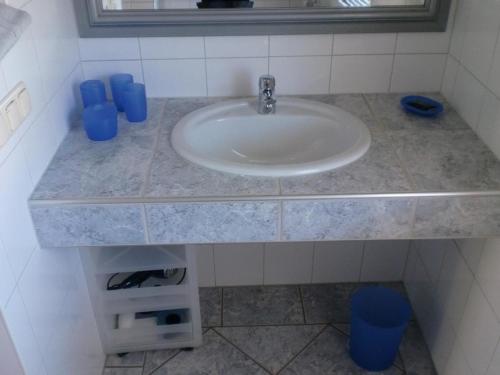 a white sink in a bathroom with blue cups at Ostseebrise 1 in Zingst