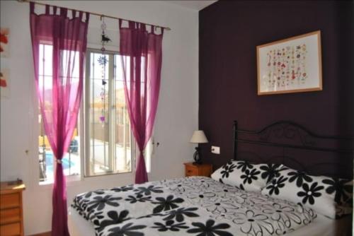 Schlafzimmer mit einem Bett und einem Fenster mit rosa Vorhängen in der Unterkunft Casa Aurelia in Mazarrón