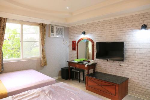 Cai-Lai Motel في Yangmei: غرفة نوم بسرير وتلفزيون ومكتب