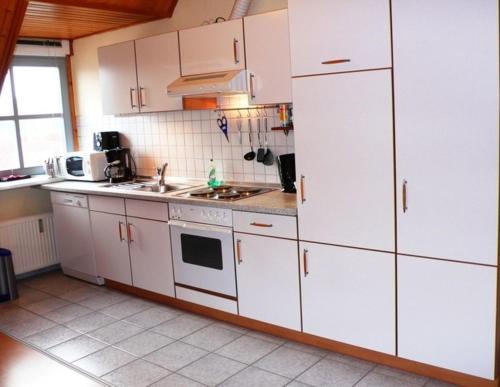 uma cozinha com armários brancos e um lavatório em Ferienwohnung Uferschwalbe em Rerik