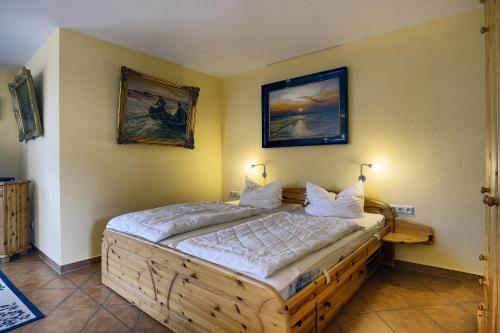 a bedroom with a wooden bed with two pictures on the wall at Kranichguck, App 1 in Zingst