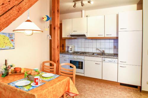 uma cozinha com armários brancos e uma mesa com comida em Landglück em Klausdorf