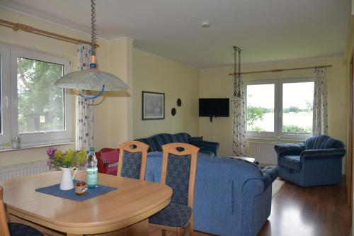 een woonkamer met een blauwe bank en een tafel bij Inselhof Steengrafe - Strandblick in Schwanewede