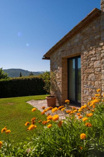 a stone house with a bunch of flowers in the yard at Cavarchino B&B in Gaiole in Chianti