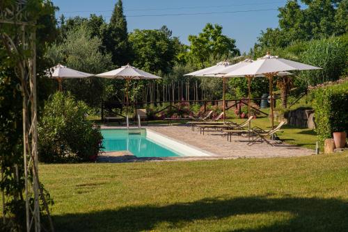 a swimming pool with two umbrellas and chairs and a pool at Cavarchino B&B in Gaiole in Chianti